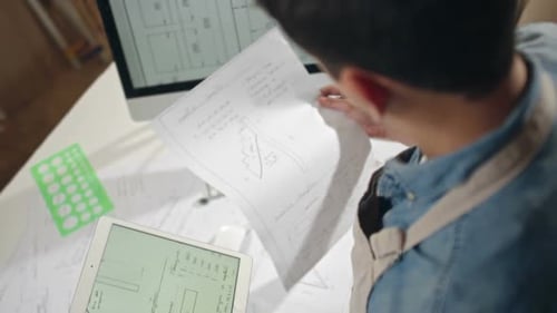 Designer Reviews Plans on Tablet and Paper