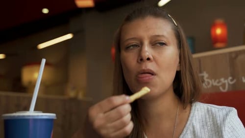 Femme dans un café de restauration rapide manger de la malbouffe