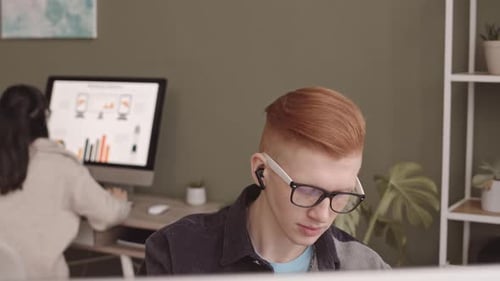 Jeune homme roux travaillant sur ordinateur au bureau