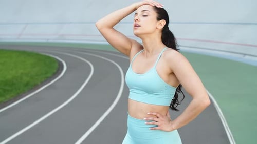 Attractive Woman Runner Taking Rest After Running Workout on Racetrack