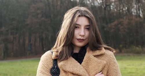 Portrait of Young Attractive Female Who Smiling and Looking at the Camera on Green Lawn. Cheerfully