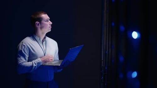 Concept of Digitalization of Information IT Specialist In Front of Server Racks with Laptop