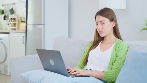 Woman Uses Laptop Computer on Sofa at Home