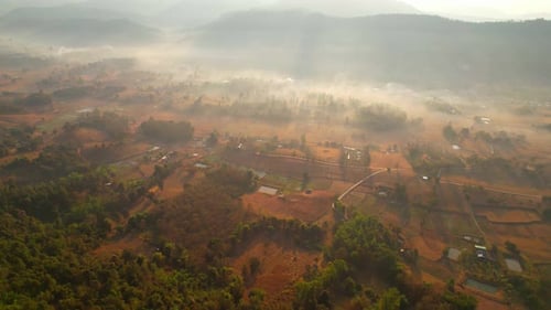 Aerial view over villages and barren fields in countryside during sunrise