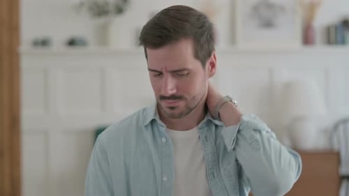 Man Massaging Stiff Neck Muscles Indoors