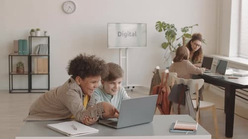 Children Collaborating on a Laptop in Bright Office