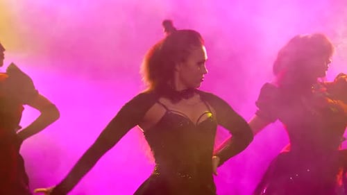 Girls Dance in Sexy Costumes. Young Hot Brunettes with Long Hair. Bright Makeup and Red Lips. Neon