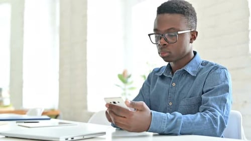 Young Adult Using Smartphone in Bright Office