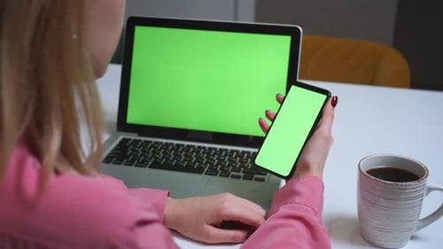 Mujer de cerca usando la pantalla verde del teléfono inteligente sobre la mesa con la computadora portátil Chromakey