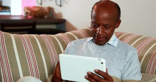 Senior Man Using Tablet on Striped Couch