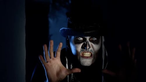 Frightening Man with Halloween Skeleton Makeup Quickly Appears From Dark Corner, Trying To Scare