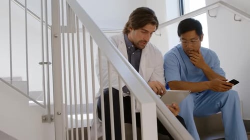 Doctors Consult Tablet and Phone on Staircase