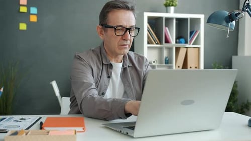 Man Working on Laptop at Desk in Office