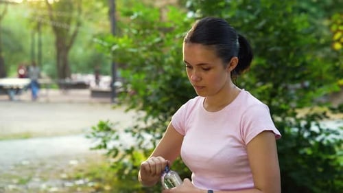 Woman Drinking Water After Jogging in Park