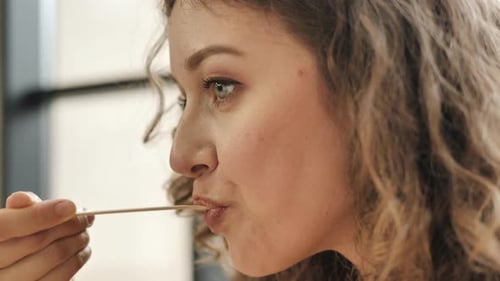 Curly Haired Lady Licks Lips Eating Food in Cafe Macro