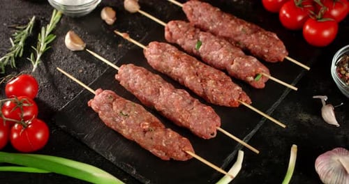 Raw Kebab Sausages on Stone Board with Tomatoes and Spices.