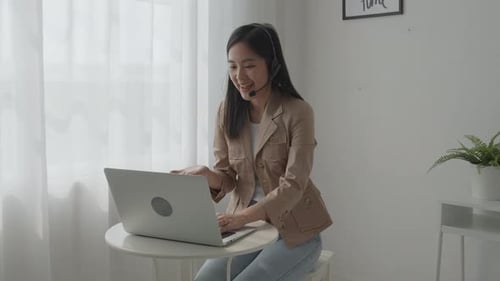 Smiling Woman Video Calling with Laptop and Headset