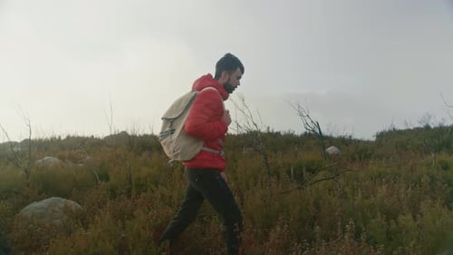 Man in Red Puffy Jacket Hiking in Windy Weather