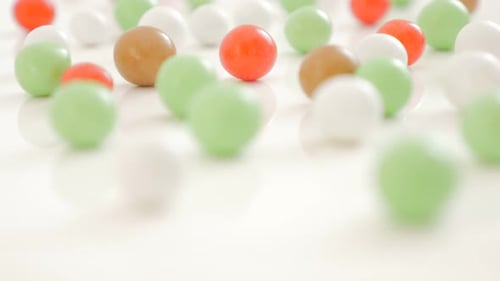 Colorful bonbons on white reflective background randomly positioned 4K 2160p 30fps UltraHD video - L
