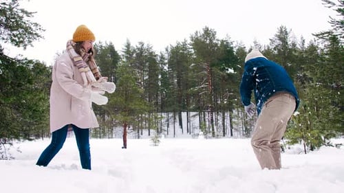 Couple having a Fun Snowball Fight in Winter
