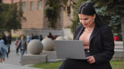 Woman Working on Laptop in City Setting