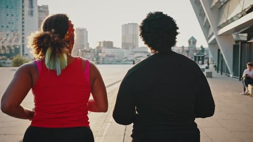 Women Jogging Together in Urban City at Sunset
