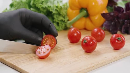 Gloved Hand Slices Tomato with Sharp Knife