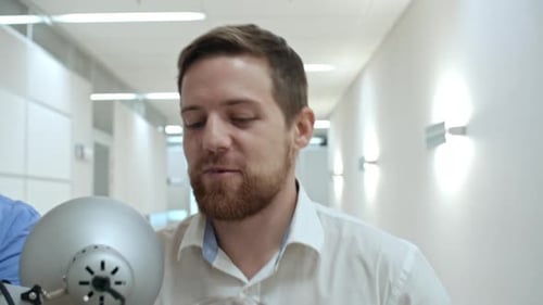 Collègues masculins transportant des affaires et discutant sur le chemin du nouveau bureau
