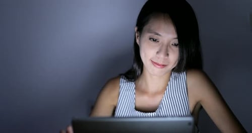 Woman using tablet computer at night