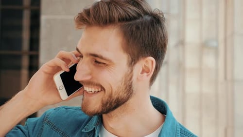 Schöner lächelnder Mann in Freizeitkleidung beim Telefongespräch