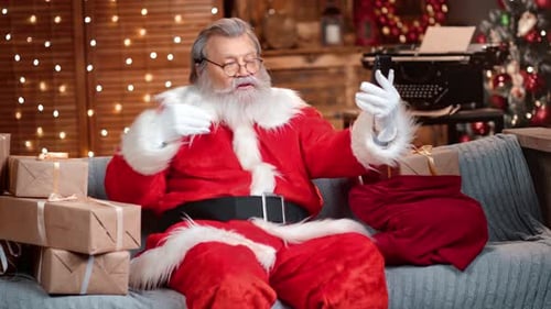 Santa Claus Using Smartphone on Sofa at Christmas