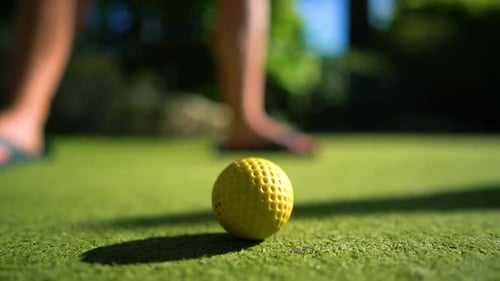 Mini Golf Yellow Ball with a Bat near the Hole