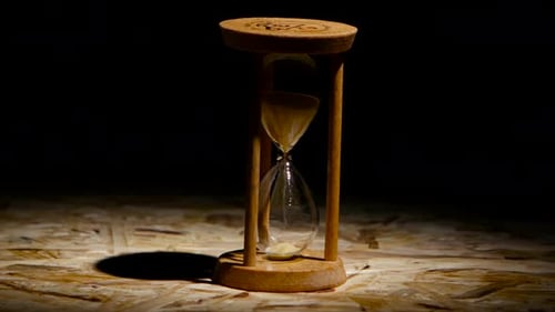Wooden Hourglass with Sand Falling Against Dark Background