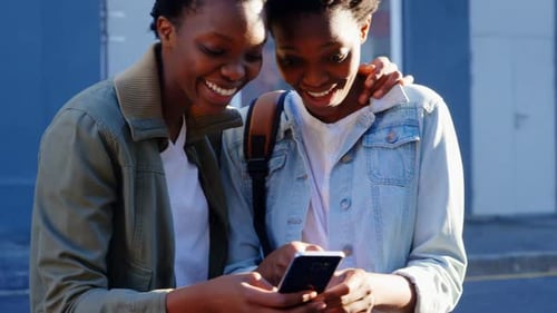 Twin sisters using mobile phone in the city 4k