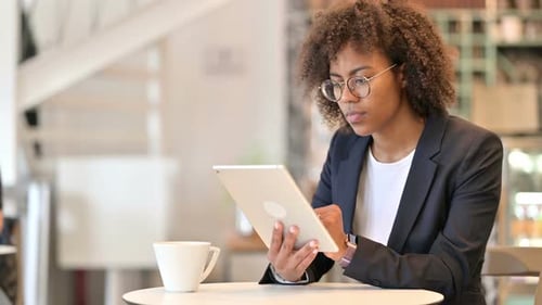 Serious Young African Businesswoman Using Tablet at Cafe