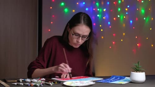 Young Woman Painting Landscape with Watercolors Indoors