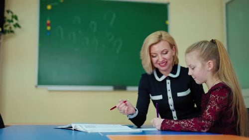Young Girl Studying with Teacher at School