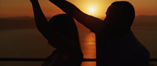 Close up of a young couple dancing and having fun at sunset, spending a romantic evening together