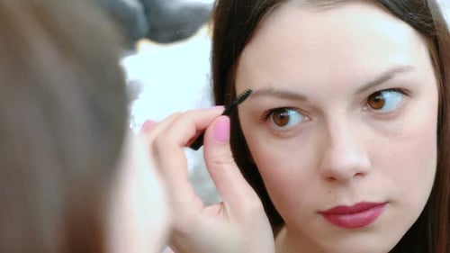 Woman Applies Makeup to Eyebrows with Brush