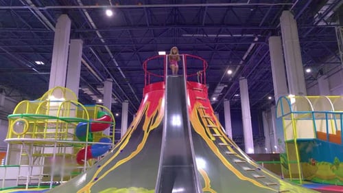 Girl Sliding Down Volcano Slide at Indoor Playground