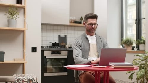 Man Works on Laptop at Home Kitchen Table