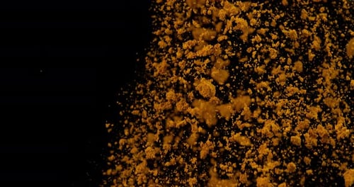 Spoon and Curry Powder falling against Black Background, Slow motion 4K
