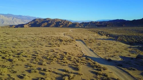 Scenic aerial drone view of dirt road and rocky desert landscape.