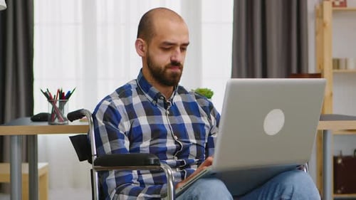 Man in Wheelchair Working on Laptop at Home
