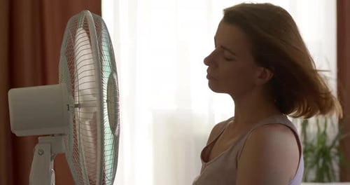 Woman Cooling Off in Front of an Oscillating Fan