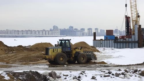 Excavator on Snowy Urban Construction Site in Winter