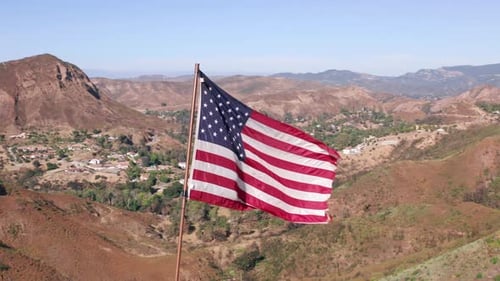 American Flag Waving in Mountain Landscape