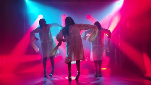 Silhouettes of a Three Charming Girls in White Shirt Are Dancing on the Stage. Shot in a Dark Studio