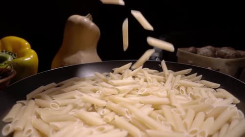 Penne Pasta Falling into Black Skillet