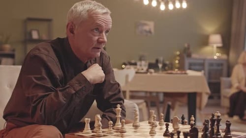 Mature Man Playing Chess in Cozy Living Room